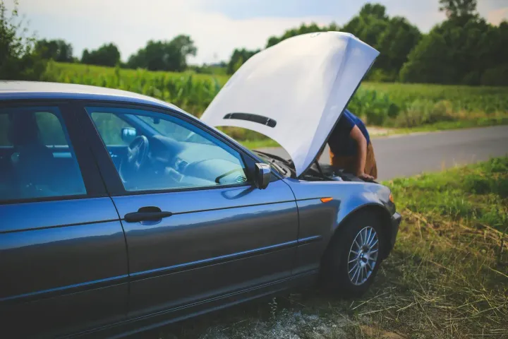Automašīna ar atvērtu motora pārsegu ceļa malā
