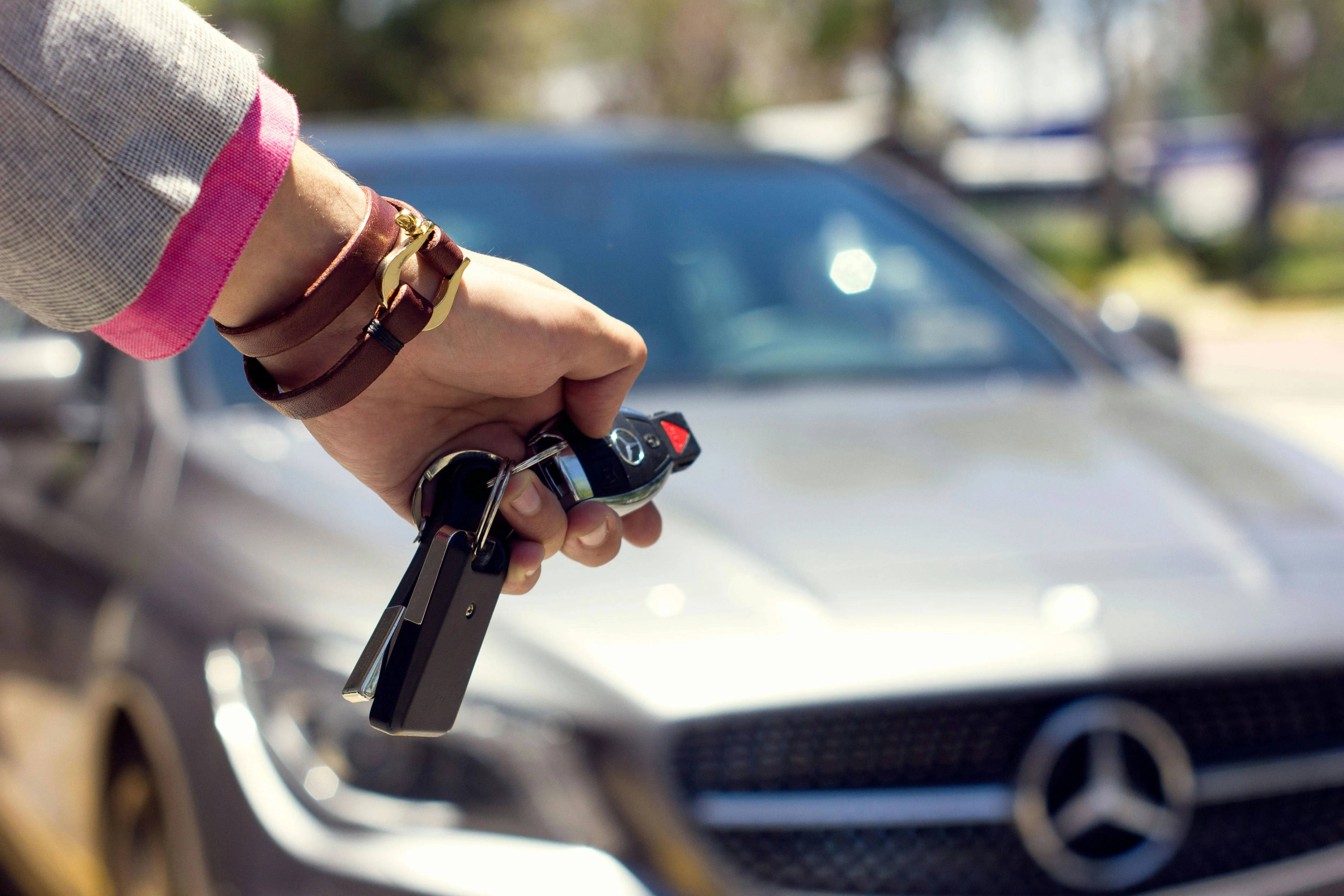 Automašīnas atslēga rokas tuvplānā ar auto fonā
